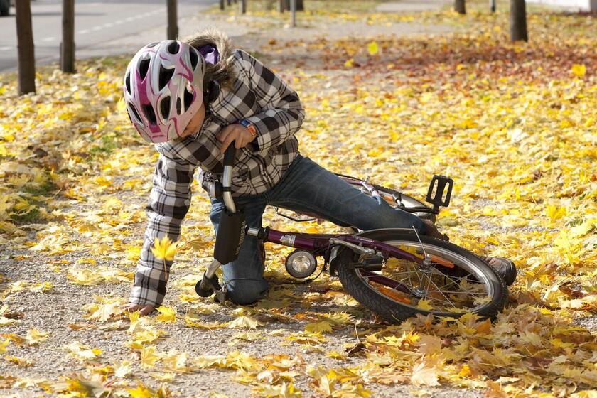 Kind stürzt mit Fahrrad auf rutschigem Herbstlaub
