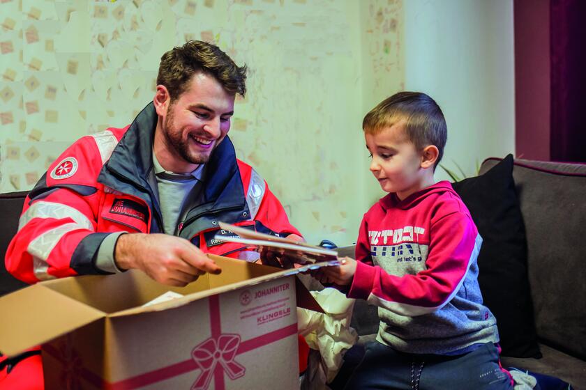 Kind packt Weihnachtstrucker-Paket aus. 