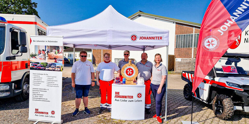 Johanniter unter einem Pavillon mit Bowlag und Roll-Ups im Johanniter-Design