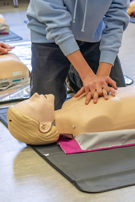 Eine Person führt eine Herzdruckmssage an einer Puppe durch.