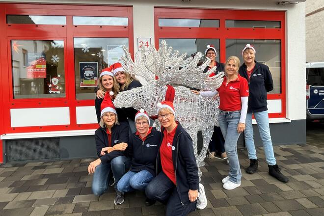 Mitarbeiterinnen und Leitungen weihnachtslich kostümiert muit Dekoelch vor dem Eingang der Tagespflege