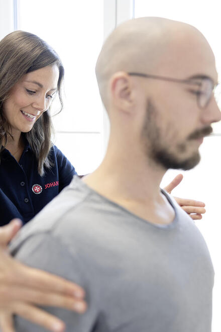 Eine Mitarbeiterin der Johanniter richtet einen Patientin an den Schultern aus.
