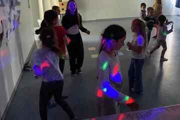 Kinder tanzen bei der Kinderdisco mit Discokugel-Licht und Musik.