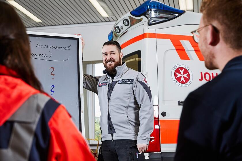 Ein Ausbilder in der Rettungsschule der Johanniter-Akademie erklärt etwas an einer Tafel.