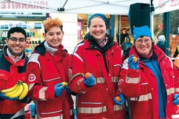 Ehrenamtliche Helfer teilen frisches Obst und Stollen an Bedürftige und Obdachlose aus.