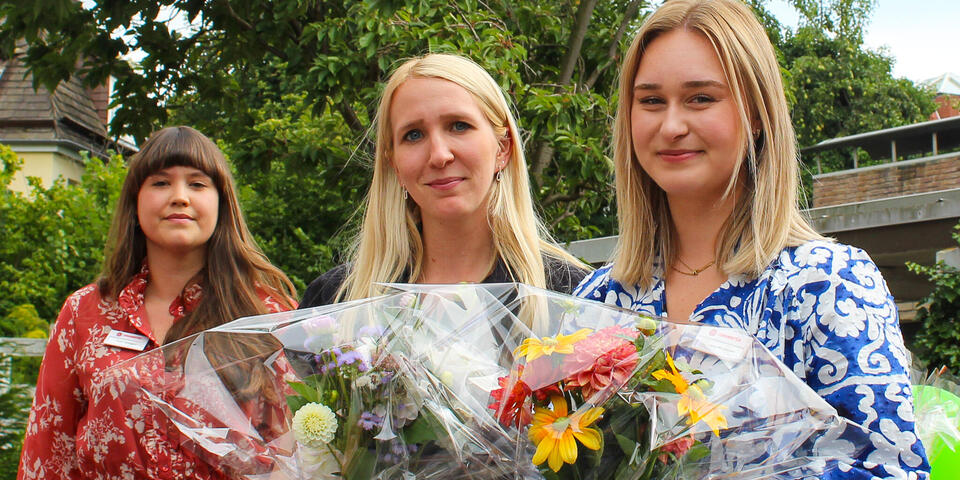 Zwei Frauen mit Blumensträußen.