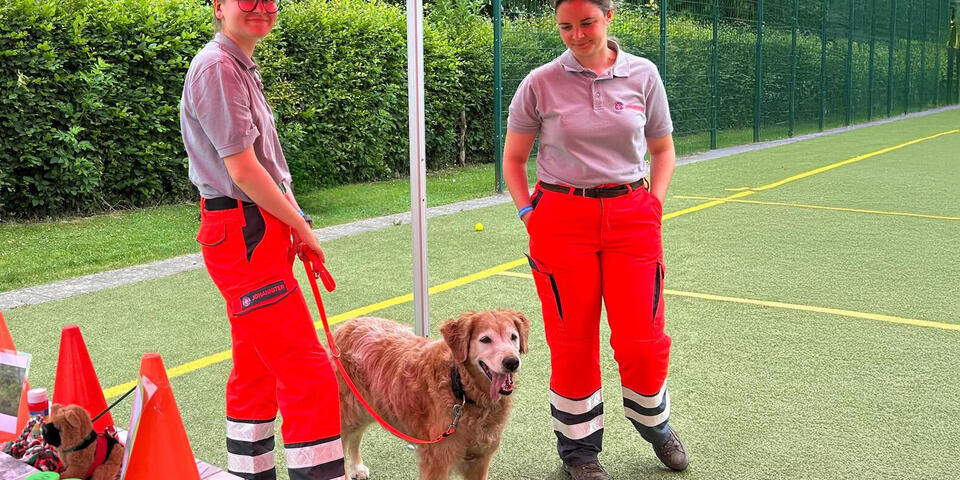 Zwei Johanniterinnen mit einem Hund unter einem Pavillon