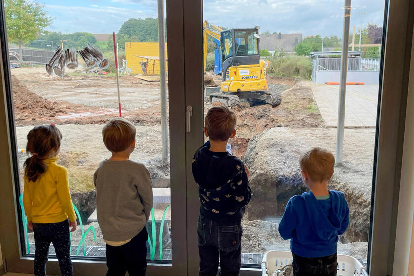 Kindergarten-Kinder schauen aus dem Fenster und verfolgen, was auf der Baustelle passiert.