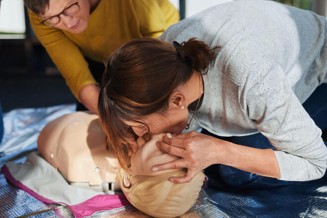 Reanimationstraining: Teilnehmerin übt Atemspende an Kinder-Dummy.