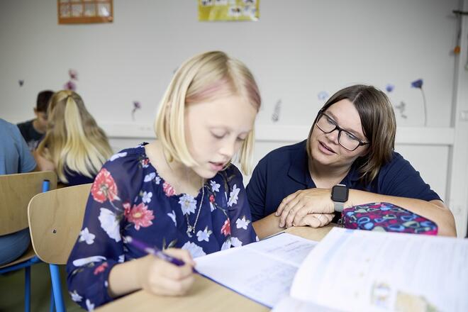 Eine Mitarbeiterin in der Johanniter Ganztagsbetreuung hilft einem Kind bei den Hausaufgaben.