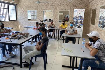 Jugendliche mit Mund-Nasen Bedeckung sitzen in einem Klassenzimmer
