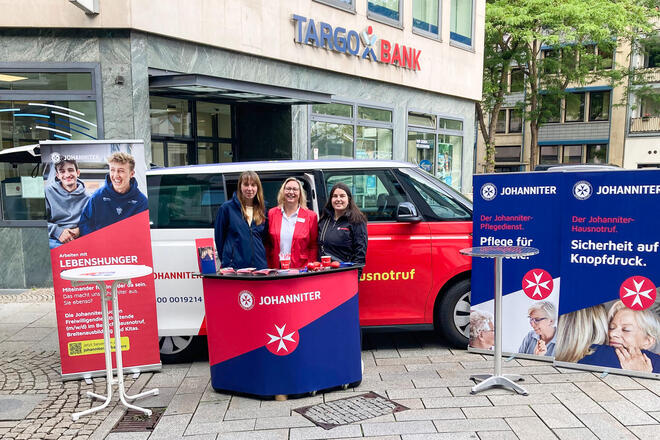Drei Frauen an einem Johanniter-Messestand in einer Fußgängerzone