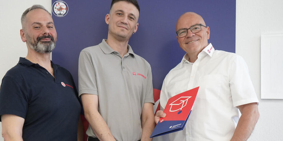 Drei Männer. Einer hält ein Zertifikat.