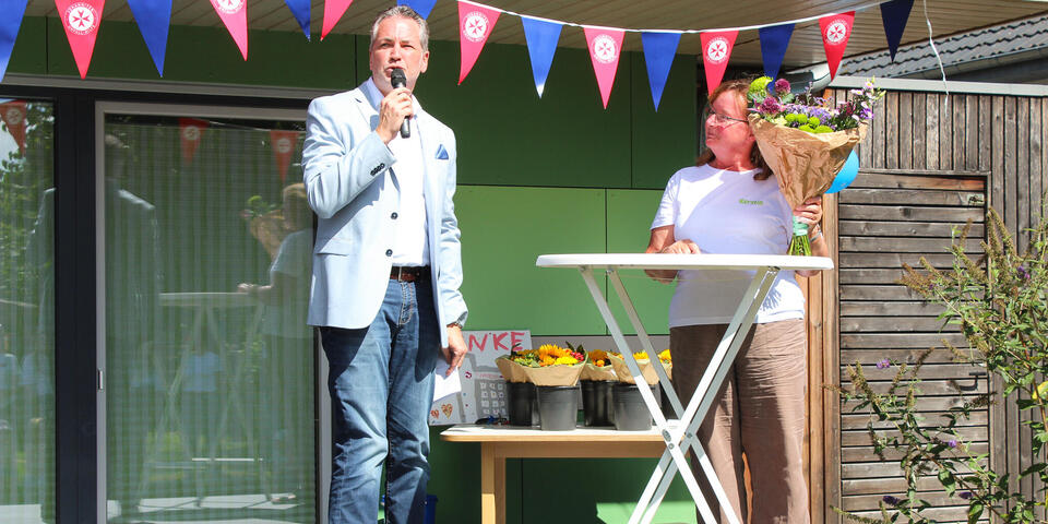 Ein Mann mit Mikro und eine Frau mit Blumenstrau0 auf einer Bühne