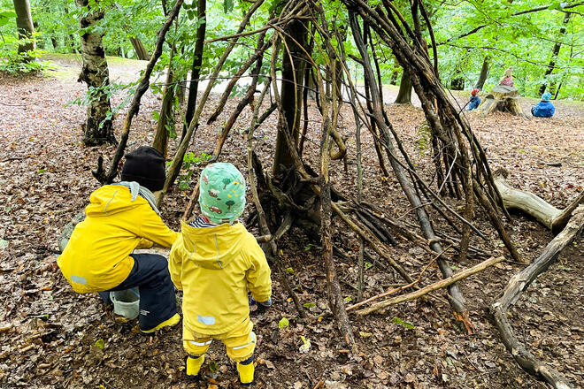 Zwei Kinder in einem Wald. Sie errichten ein Holztipi