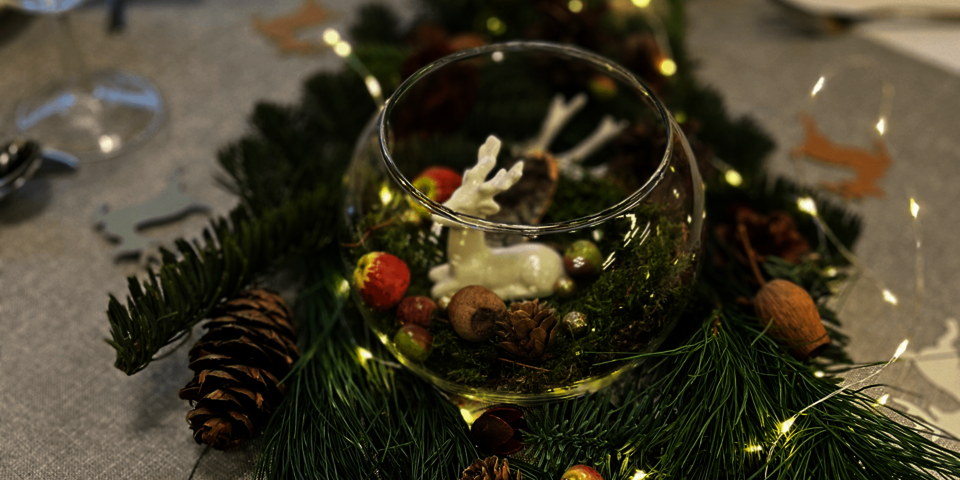 Detail der Tischdekoration mit Tannengrün, Zapfen und weihnachtlichen Elementen