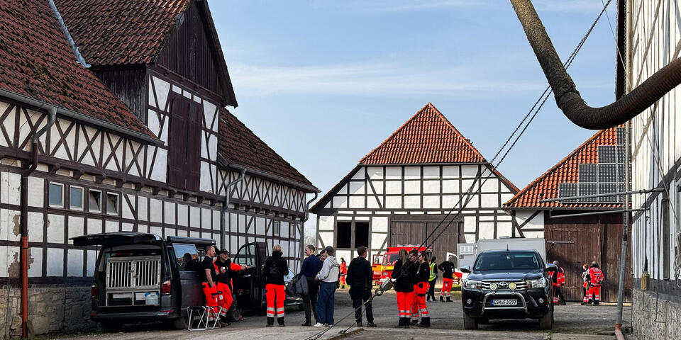 Zwischen Fachwerkgebäuden stehen Einsatzkräfte und Fahrzeuge mit Hundeboxen.