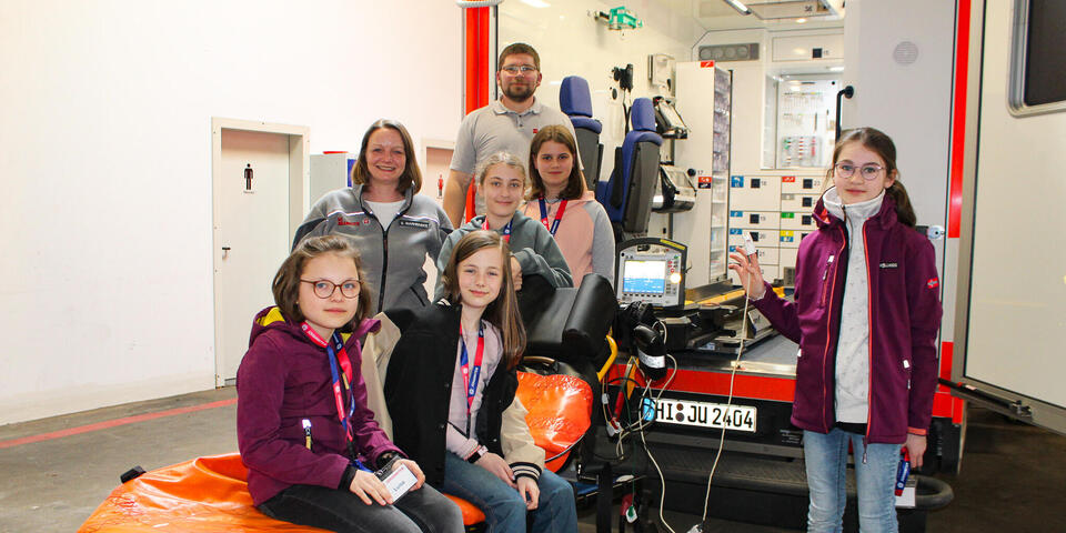 in Mann, eine Frau und drei Mädchen vor einem RTW