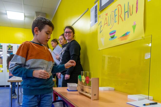 Ein Junge wirft eine kleine Kugel in das Reagenzglas mit de Bewertung.