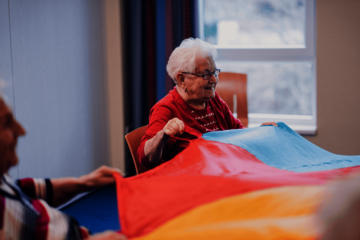 Bewohnerinnen bewegen sich mit einem bunten Schwungtuch