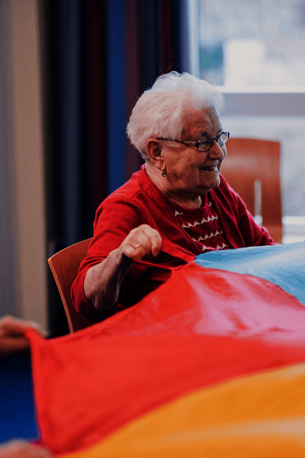 Bewohnerinnen bewegen sich mit einem bunten Schwungtuch