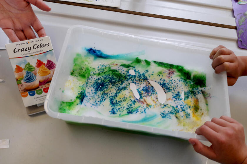 Bei einem Kreativ-Projekt in der Mittagsbetreuung Obertrubach gestalten die Kinder duftendes Papier mit Badeschaum und Farbe.