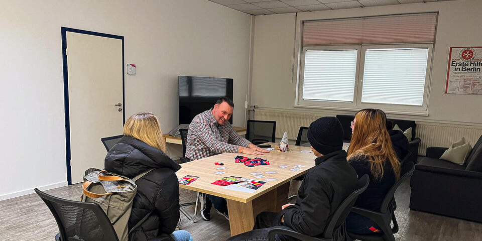 Mehrere Schüler und Schülerinnen sitzen mit einem Mann an einem Tisch.