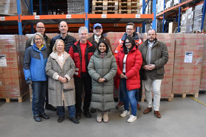Zehn Beteiligte, die gemeinsam die Pakete für den Johanniter-Weihnachtstrucker packten, stehen in der Logistikhalle 