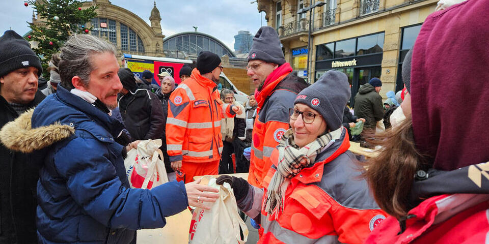 Mehrere Johanniter verteilen Geschenkbeutel an Gäste der Johanniter-Suppenküche.