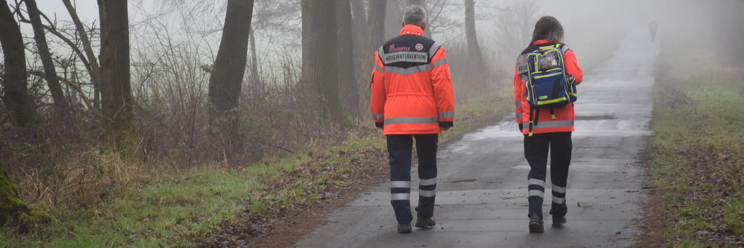 zwei Mitarbeiter des Kriseninterventionsteams laufen einen Weg entlang