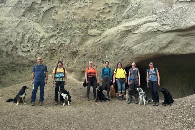 Team der Rettungshundestaffel posiert ganz privat in Mayen vor einer Trasshöhle mit ihren Hunden