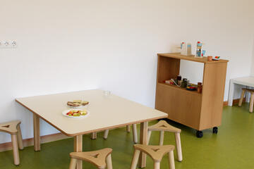 Kleiner Tisch mit Minihockern. AUf dem Tisch steht ein Teller mit frischem Obst. 