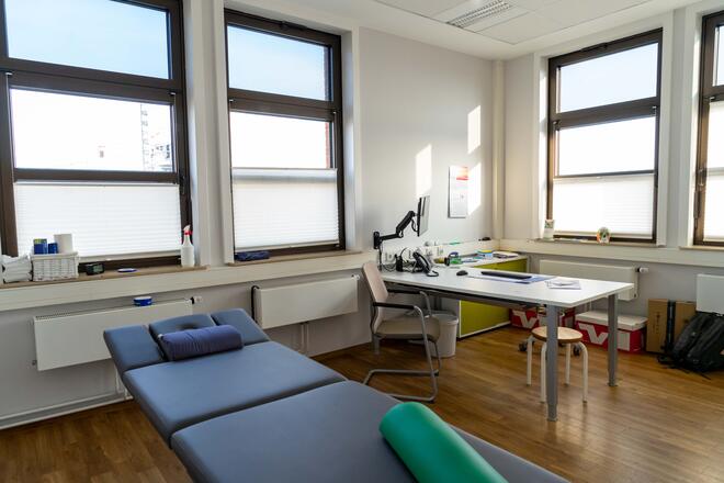 Behandlungszimmer mit Behandlungsliege und Schreibtisch in der Physiotherapie am Drägerwerk der Johanniter.