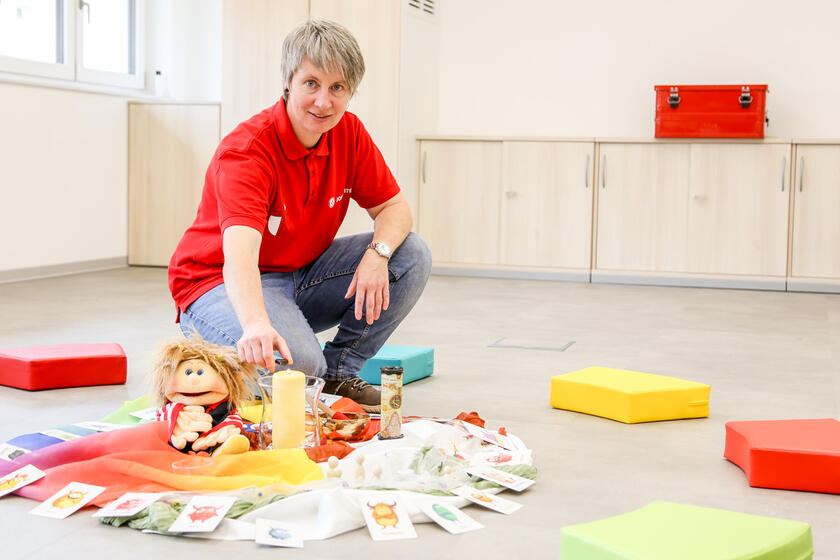 Trauerbegleiterin Bettina Wimmer zündet im neuen Raum eine Kerze inmitten bunter Karten und Tücher an.