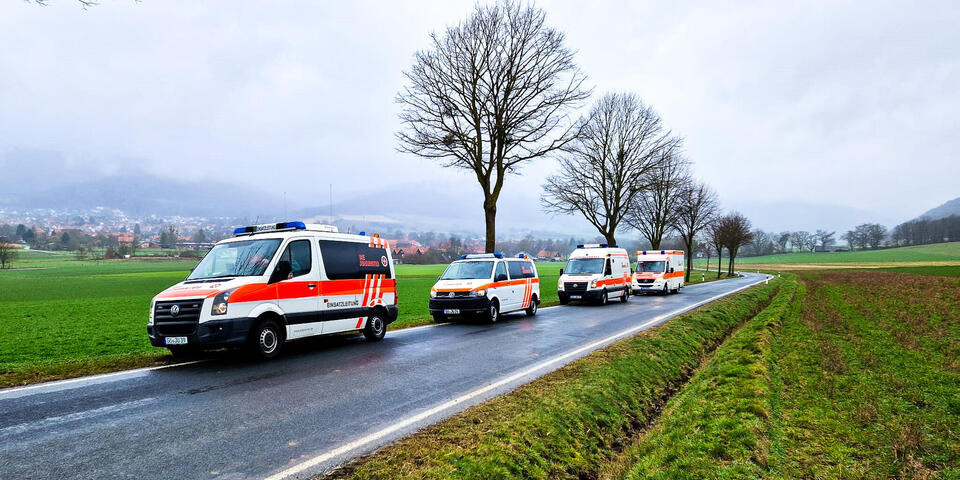 Fahrzeuge der JUH stehen am Straßenrand mit Blick auf weite Felder