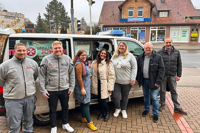 Zwei Johanniter, zwei Frauen und zwei Männer vor einem mit Weihnachtstruckerpaketen vollbeladenen Johanniter-Transporter