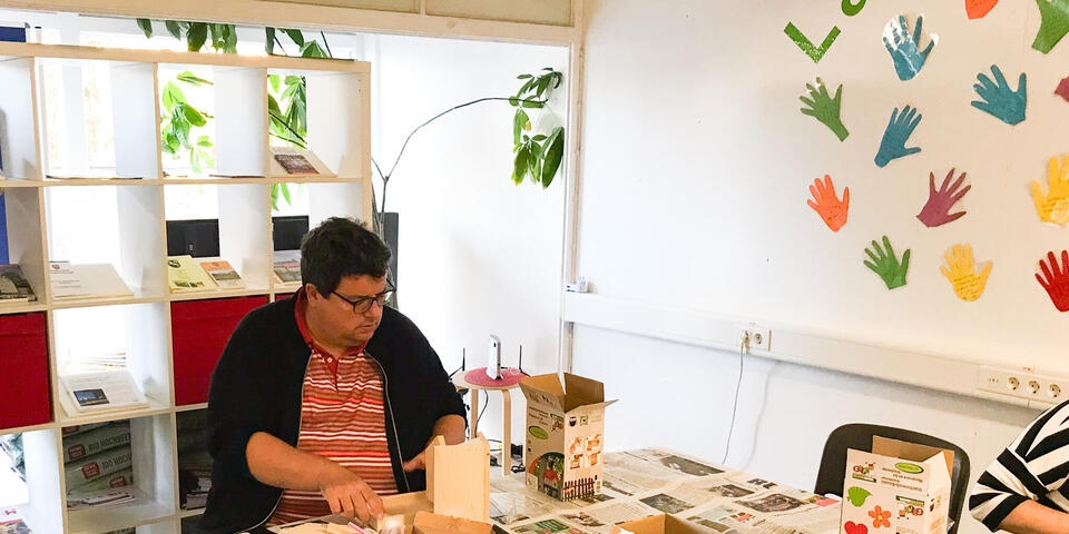 Ein Mann an einem Tisch baut einen Fledermauskasten aus Holz