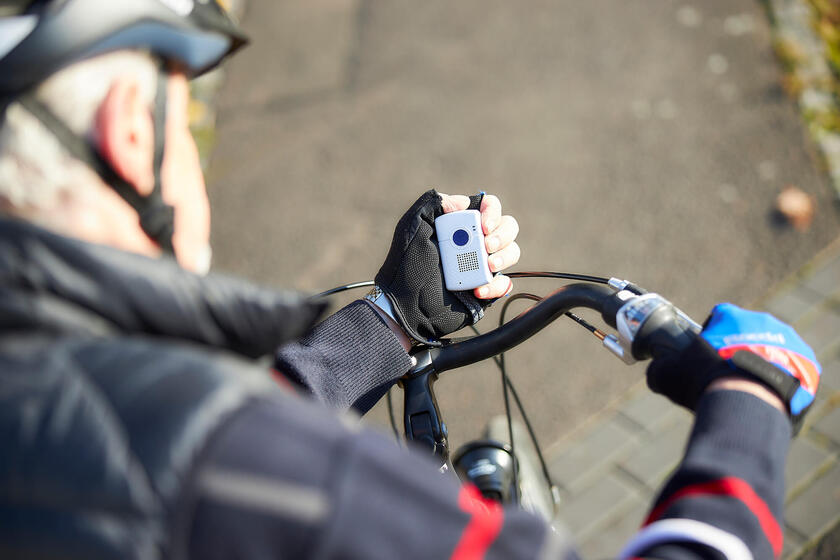 Ein älterer Mann trägt das Kombinotrufgerät beim Fahrrad fahren.