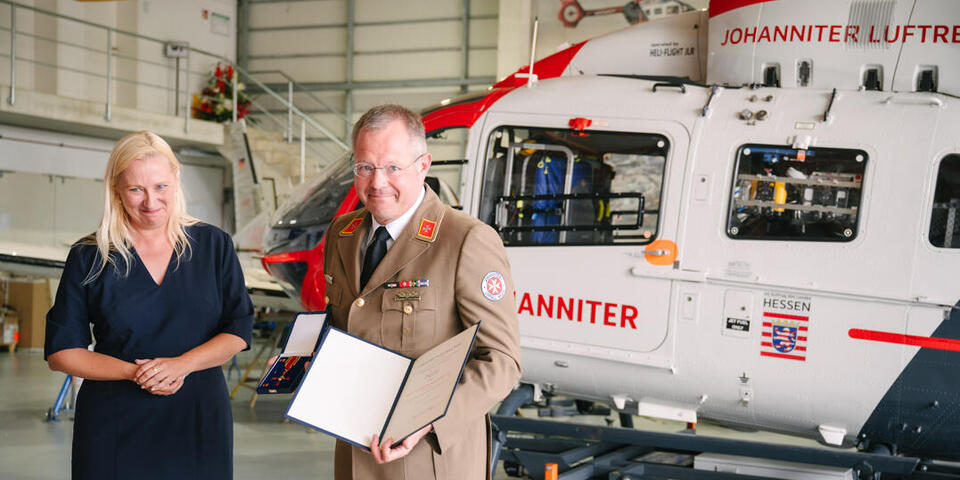 Professor Little hält Urkunde und Orden in seinen Händen.