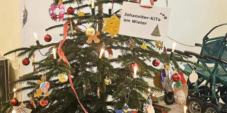 Ein geschmückter Weihnachtsbaum mit einem Anhänger auf dem Johanniter-Kita am Wieter steht