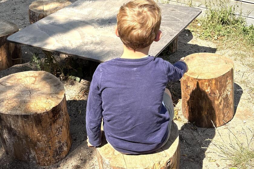 Kind sitzt auf Sitzbaustamm