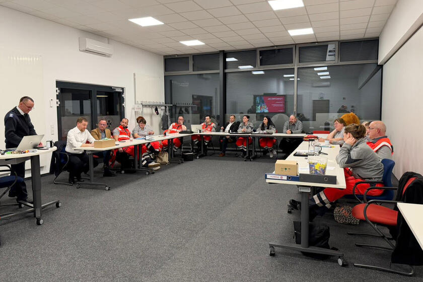 Tische sind in U-Form aufgestellt und an ihnen sitzen die Ehrenamtlichen und Herr Kretschmar