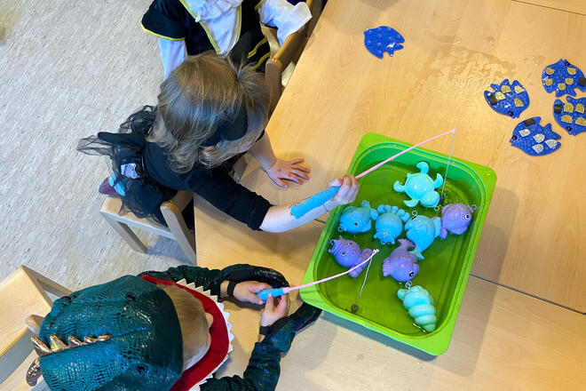 Kinder angeln Plastikfische in einer grünen Schale
