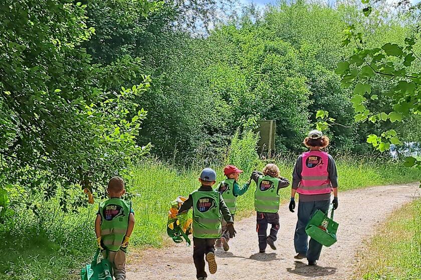 Kinder laufen mit Erzieher durch den Wald