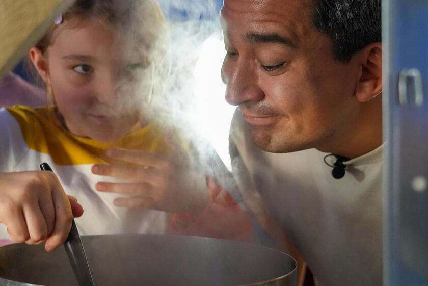 Ein Mädchen rührt in einer Schüssel, während Tohru Nakamura am aufsteigenden Dampf schnuppert.