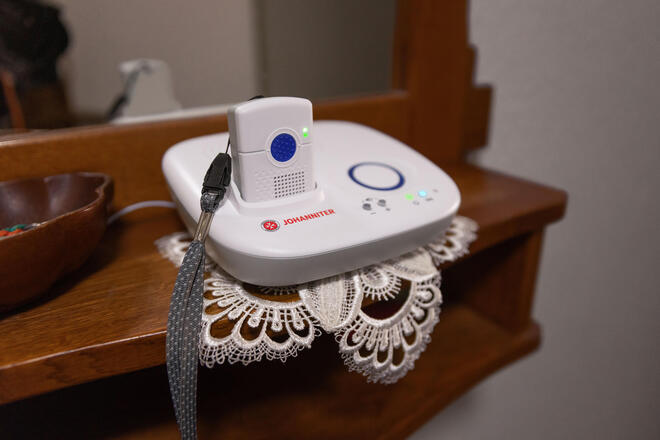 Basisstation des Johanniter-Kombinotrufs im Flur auf einer dunklen Holzkommode.