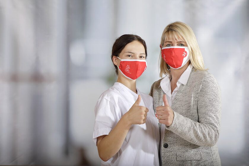 Zwei Pflegemitarbeiterinnen mit roten Johanniter-Masken