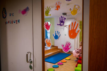 Bunte Handabdrücke der Kinder schmücken eine Fensterscheibe vor dem Bewegungsraum