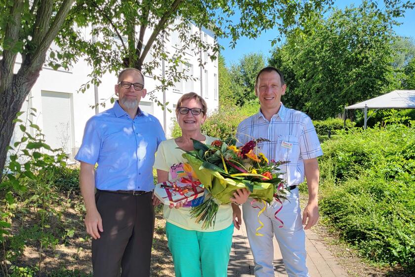 Glückwünsche, Blumen und Pralinen überbrachten  Prokurist Christian Umlauf (links)  und Einrichtungsleiter Kai Schramm (rechts) der Pflegedienstleiterin Ute Leder anlässlich ihres 35-jährigen Dienstjubiläums.