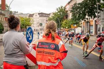 Zwei Rettungssanitäterinnen stehen am Straßenrand des Berlin Marathons.